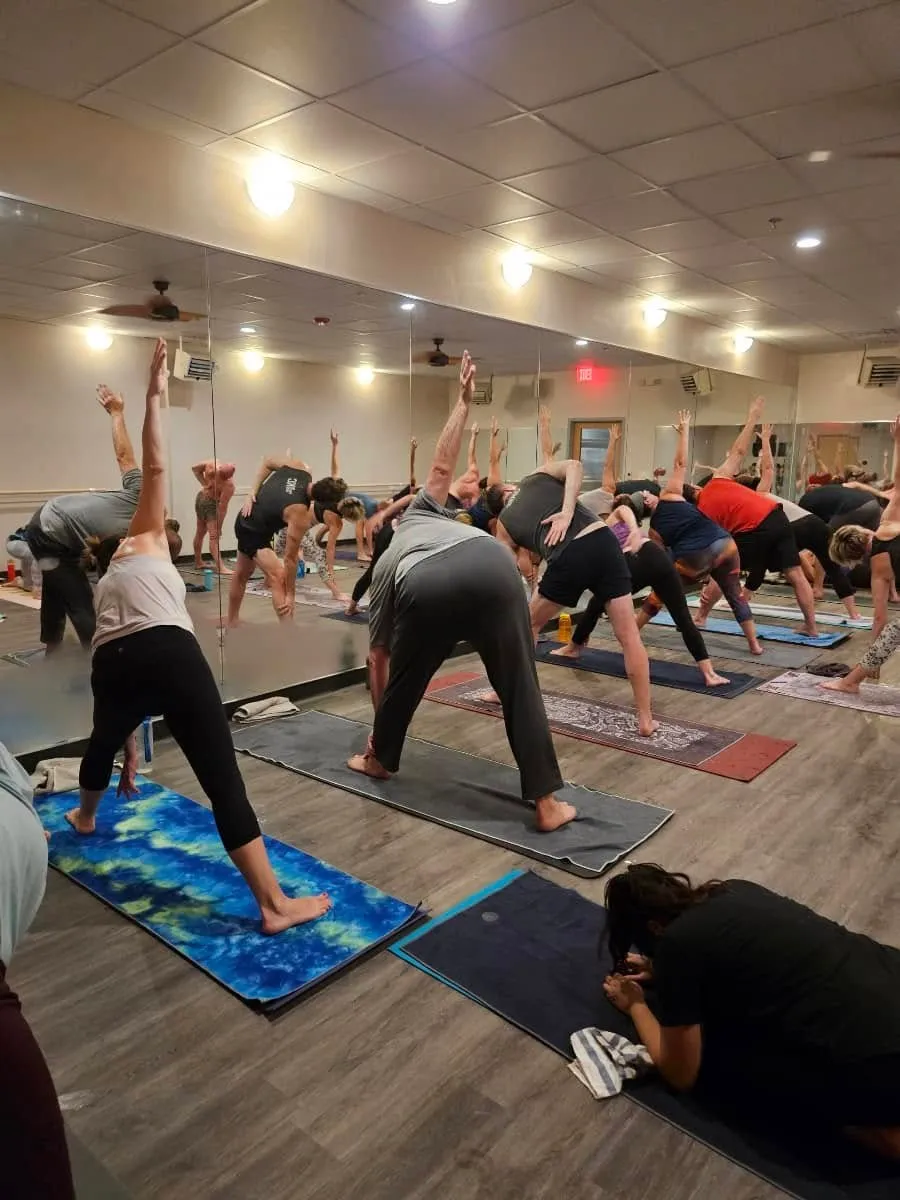 Triangle pose practice with mirror reflections during a hot yoga class